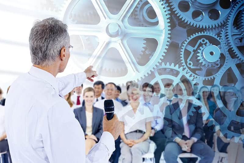 Man giving a speech with a background illustration of a cogwheel, Concept of working together