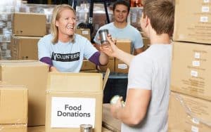 Volunteer packing canned food in a food donation box, Food donation drive