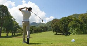 Man playing golf on a golf court on a bright sunny day