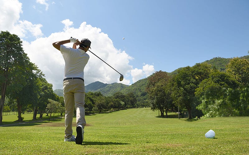 Man playing golf on a golf court on a bright sunny day