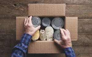 Closeup view of man placing can foods in a box