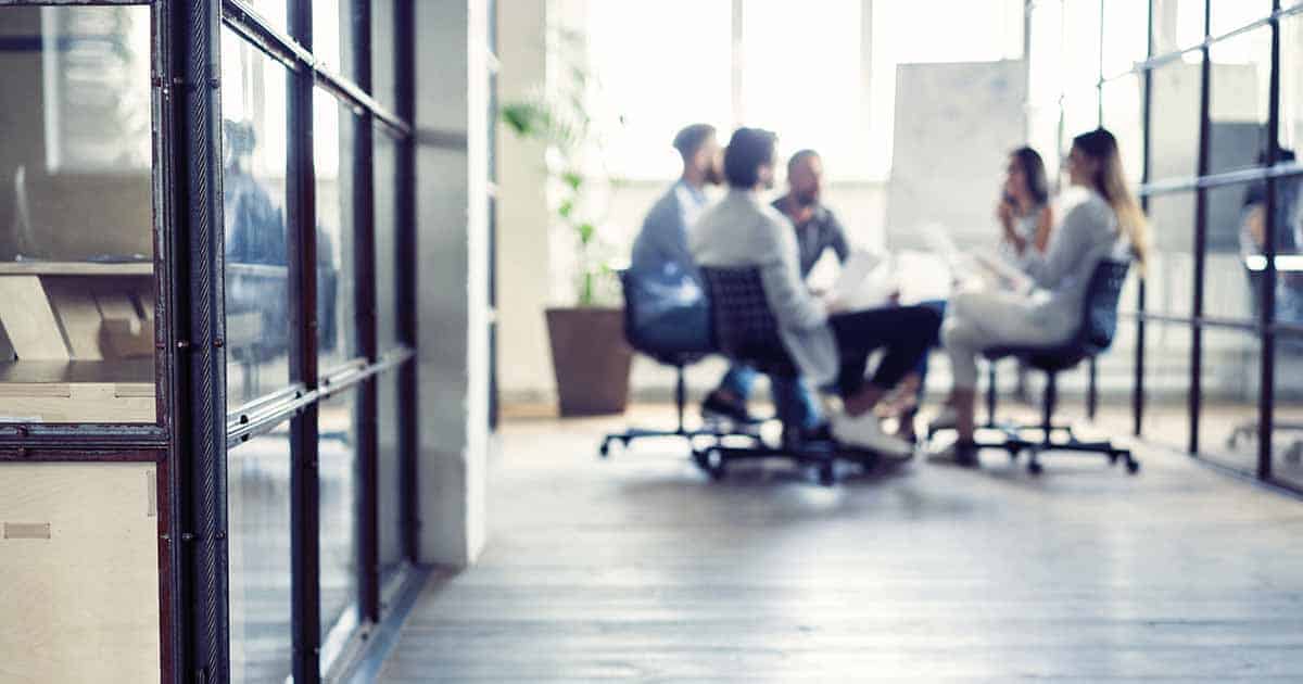 Blurred out group of people discussing at a table in office