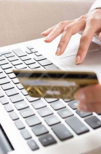 Closeup view of female hands holding credit card and using a laptop