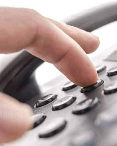SIMM Associates, Inc. provides first party customer service Closeup view of fingure dialing a telephone number on landline phone