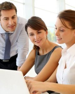 Group of businesspeople looking at laptop screen discussing work